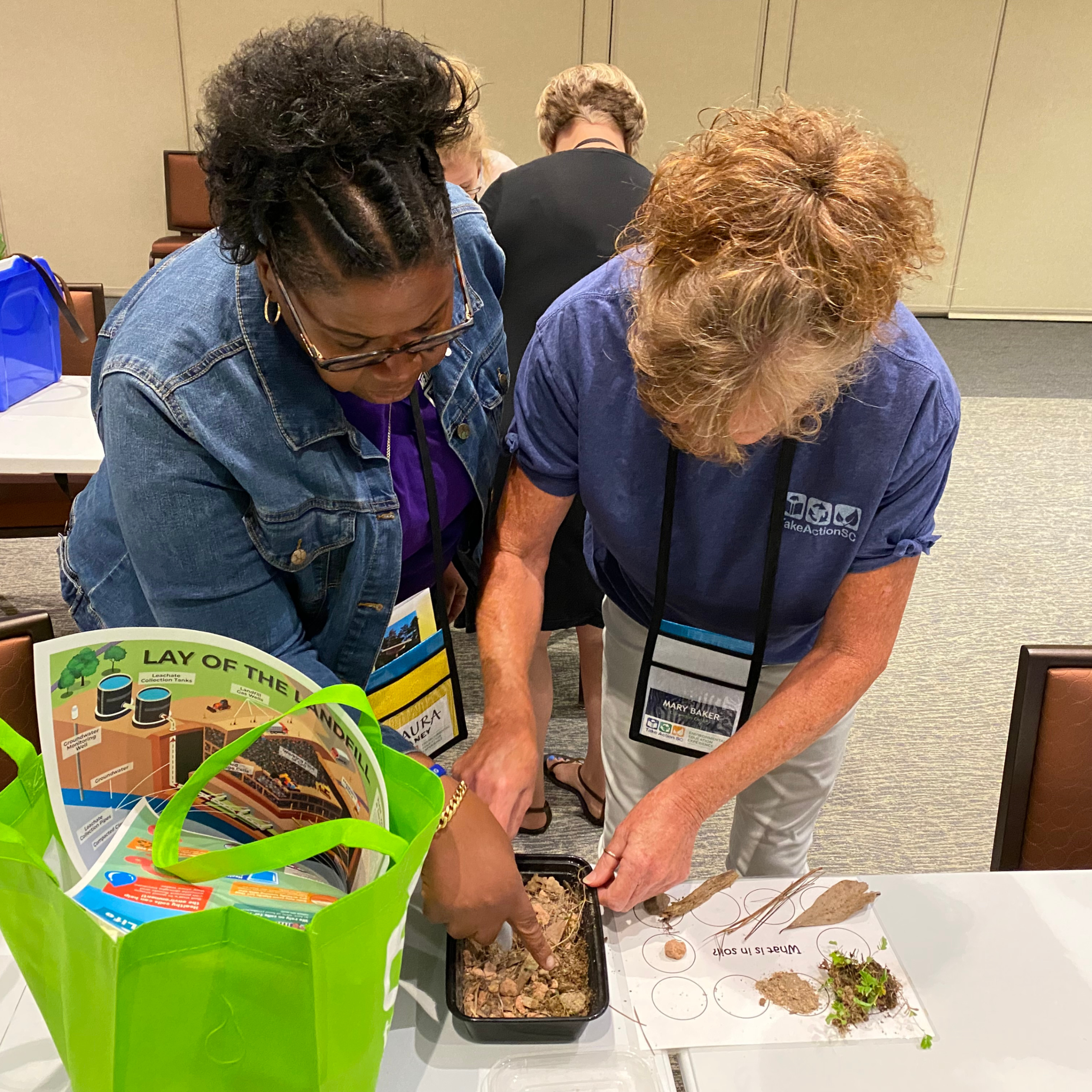 Two educators studying the contents of a soil sample.