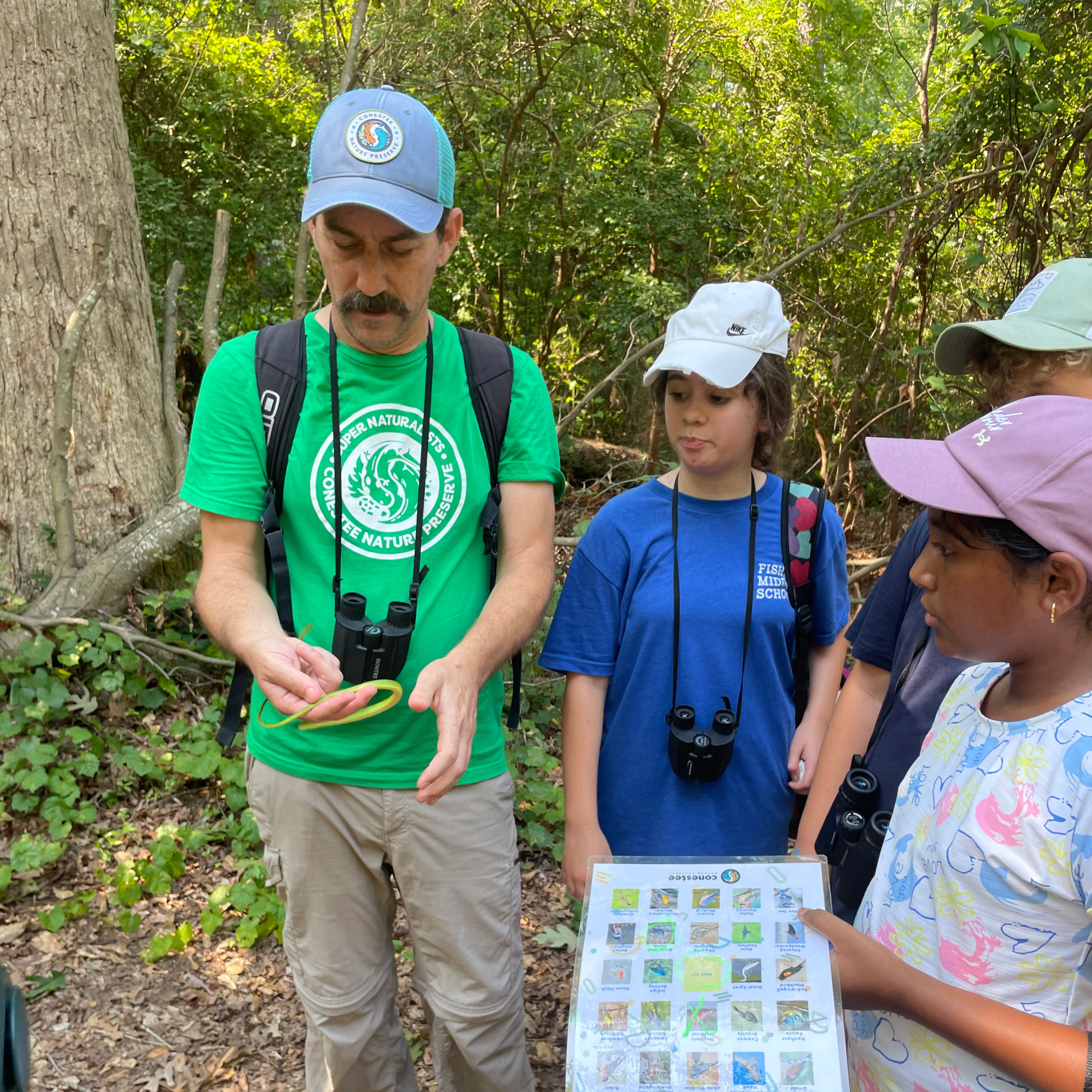 A group of students on a field trip, holding binoculars and a species identification sheet.