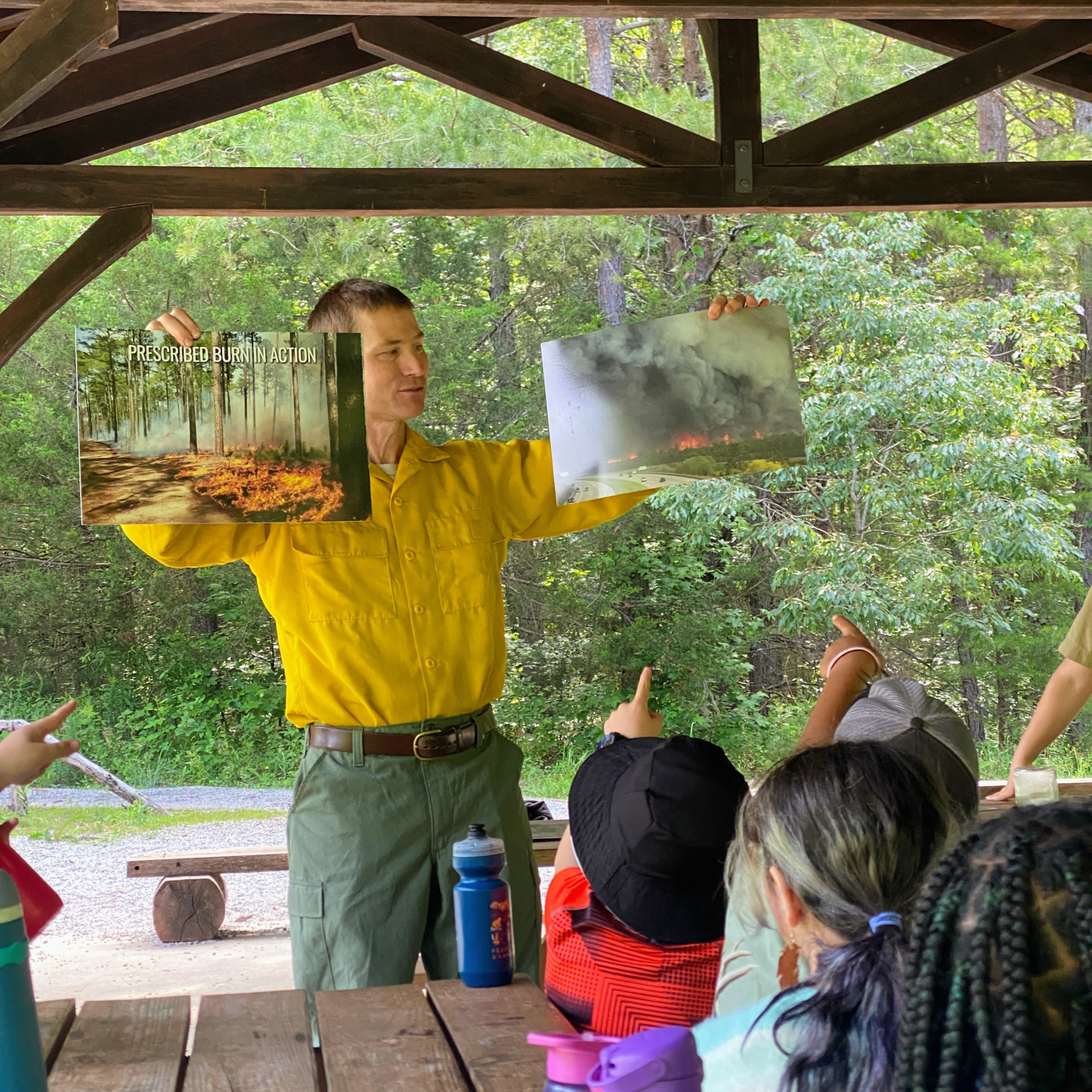 Fireman holding up pictures of prescribed forest burns.