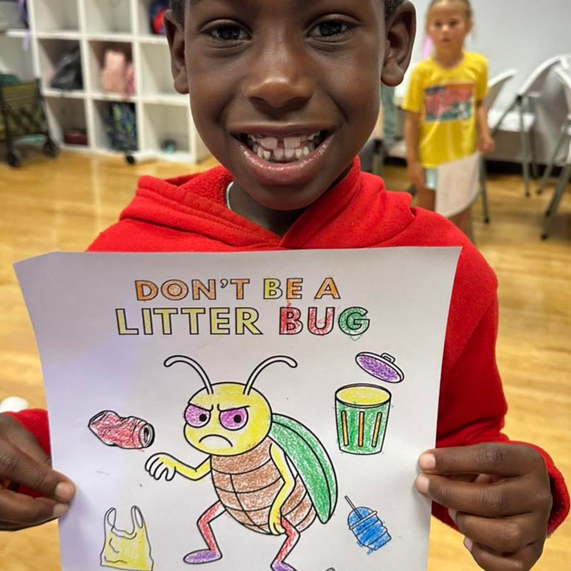 Teach Young boy holding up coloring book page with title "Don't Be a Litterbug" with cartoon illustration of a grumpy beetle.